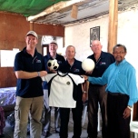 Paul Singer, Mark Fraser, Phil Singer and John Fraser handing over the sporting equipment to Father Tiago which was donated by the Gungahlin United Football Club.